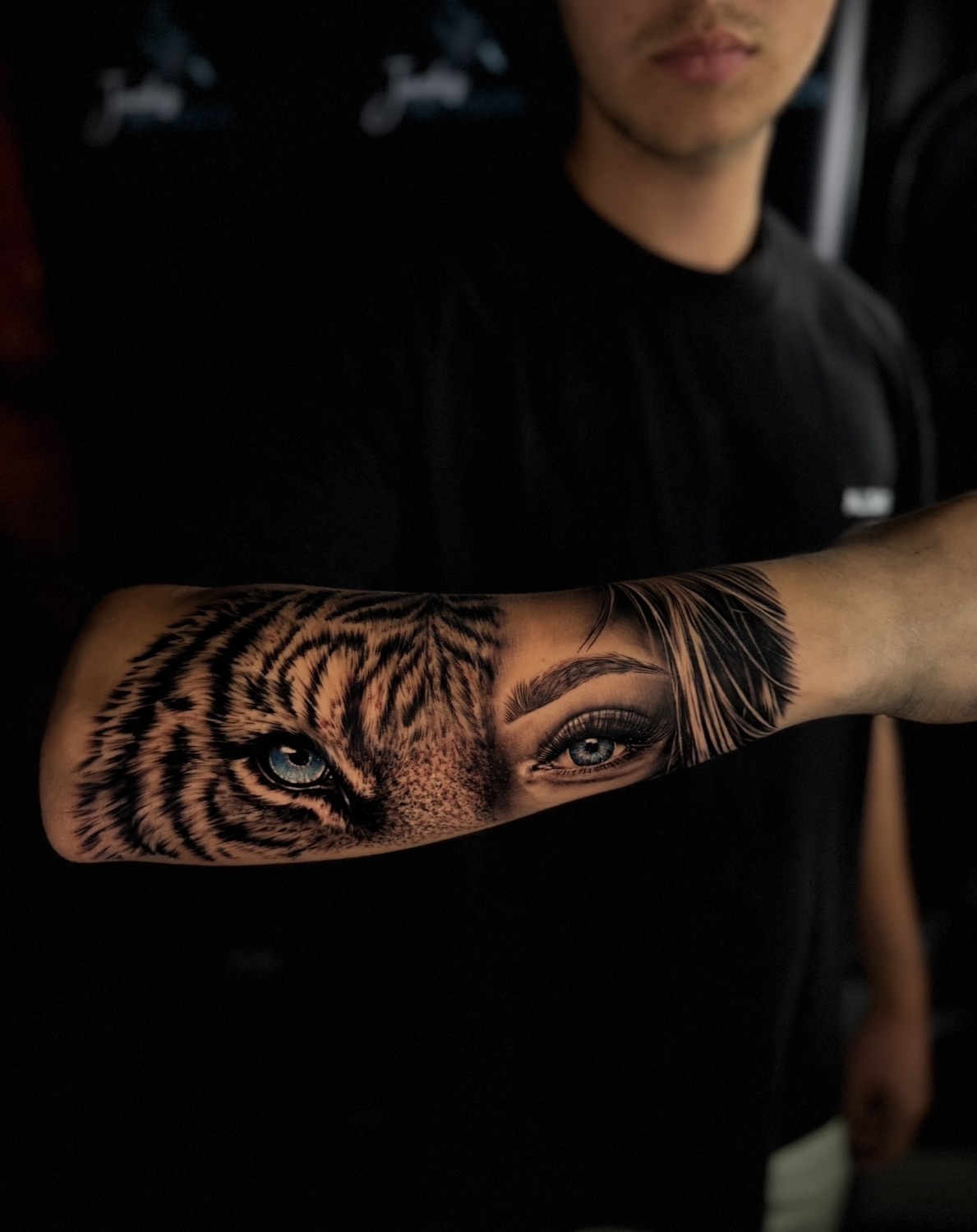 Black and grey realism tiger eye and woman's eye forearm tattoo