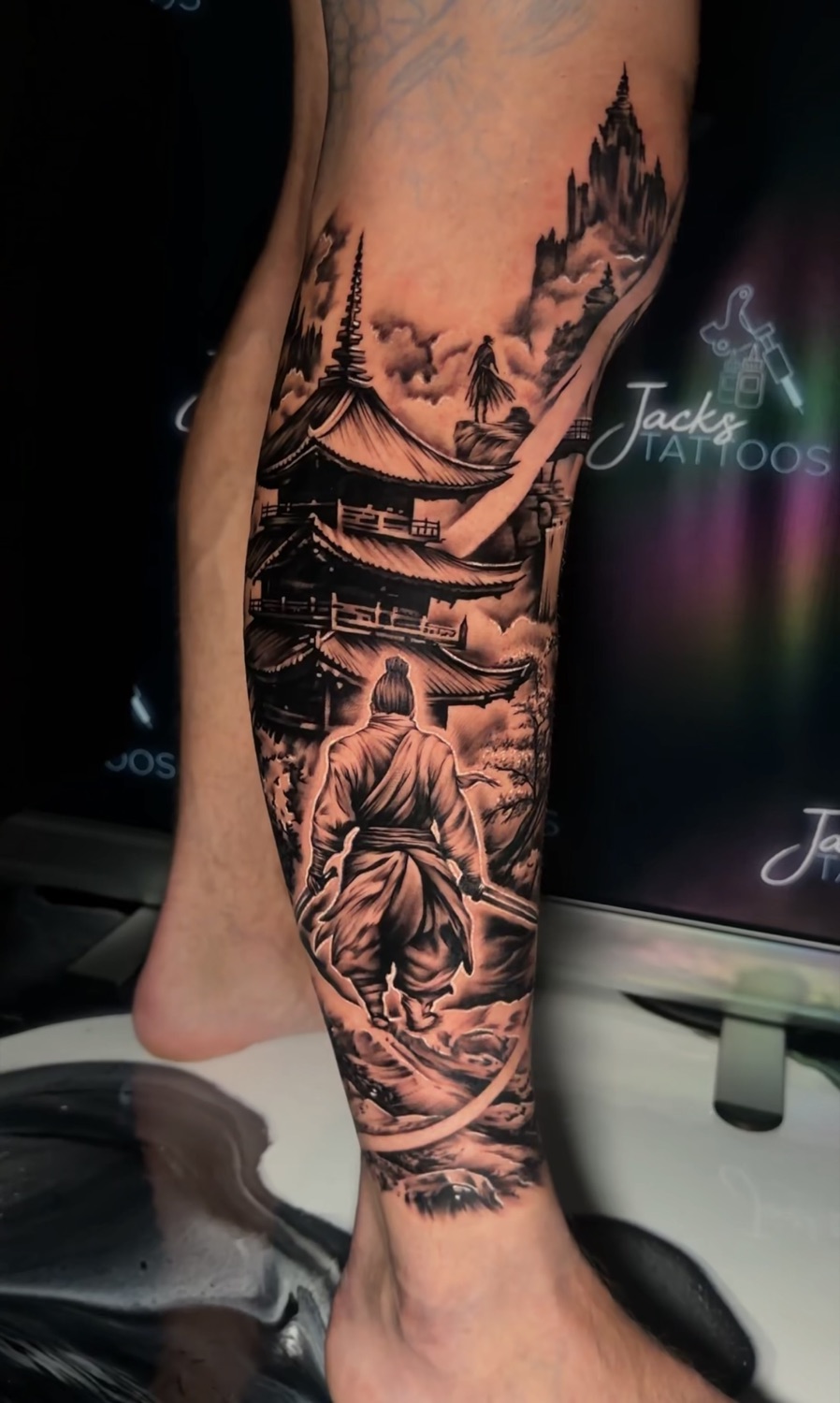 Black and grey Japanese pagoda and samurai lower leg tattoo