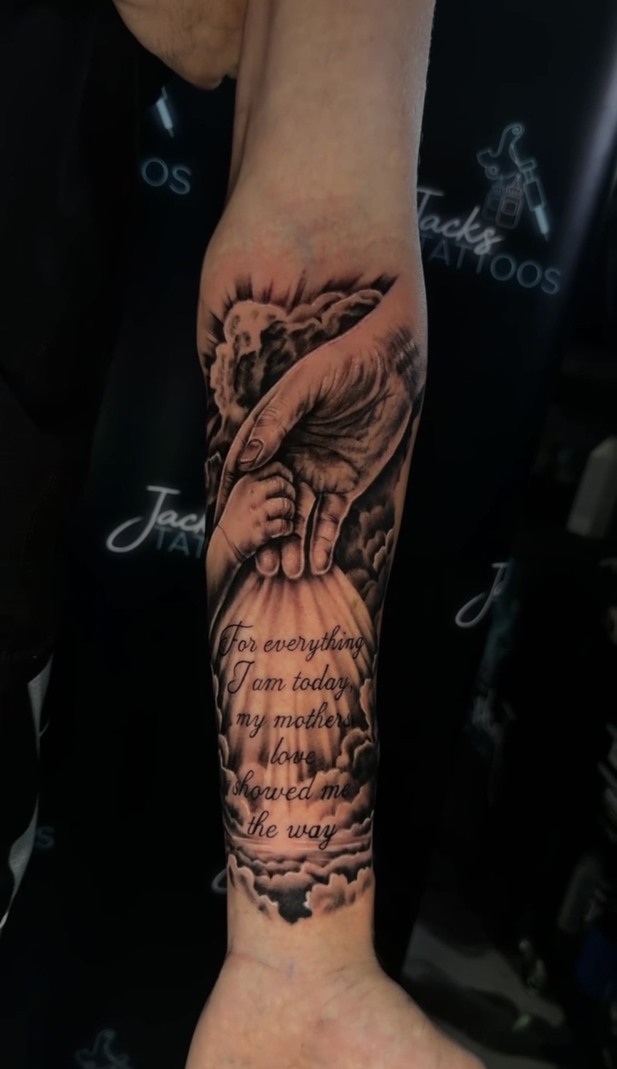 Black and grey hands and dedication script forearm tattoo
