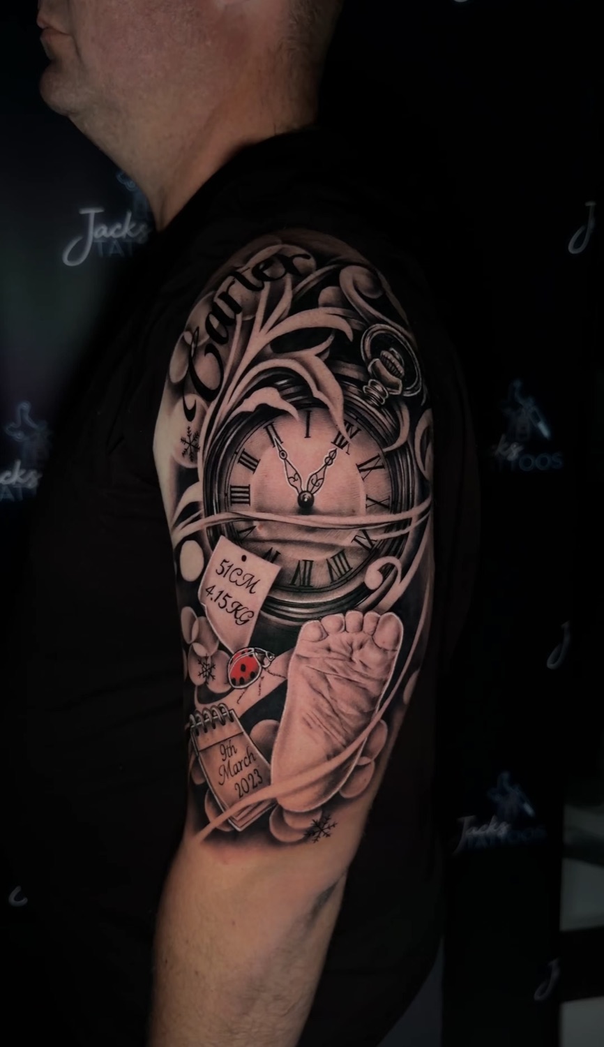 Black and grey pocket watch and baby footprint memorial upper arm tattoo