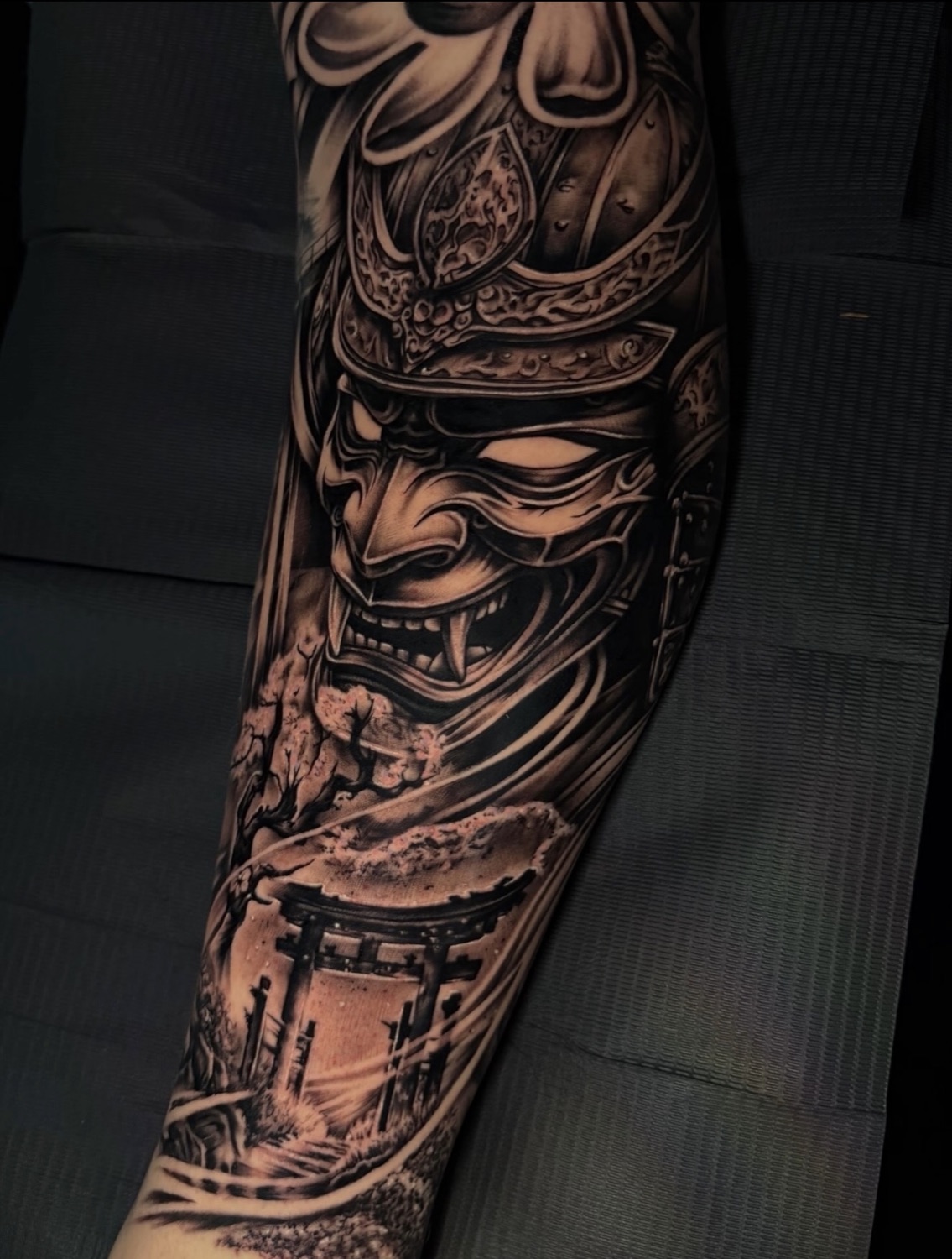 Black and grey samurai mask and pagoda forearm tattoo