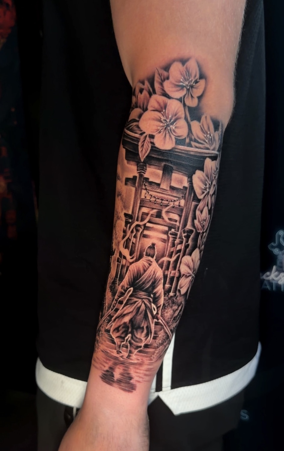 Black and grey Japanese pagoda and cherry blossom forearm tattoo