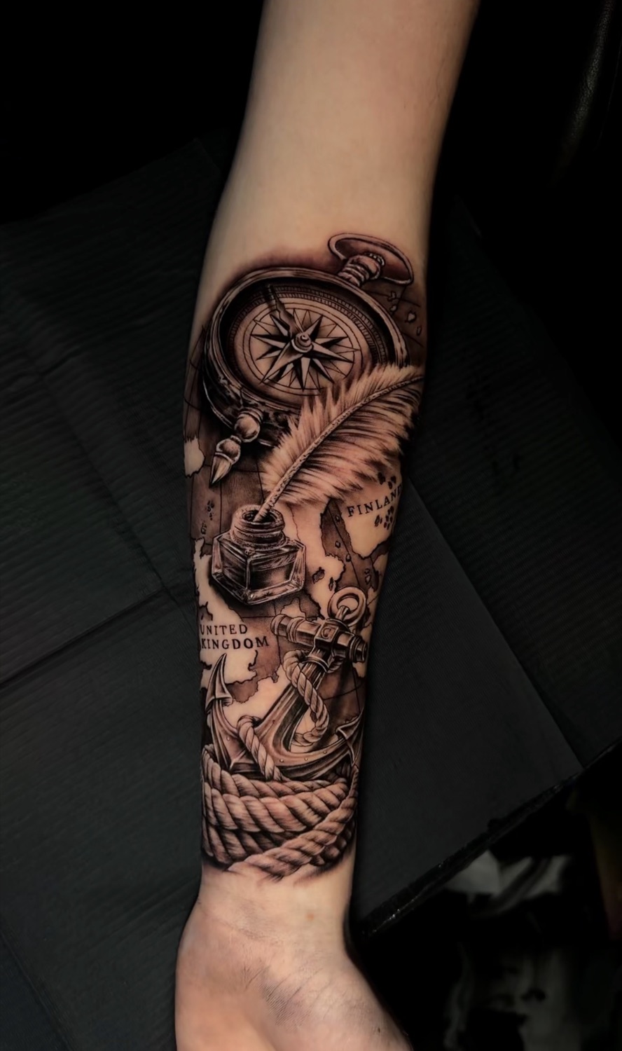 Black and grey compass, quill and anchor forearm tattoo
